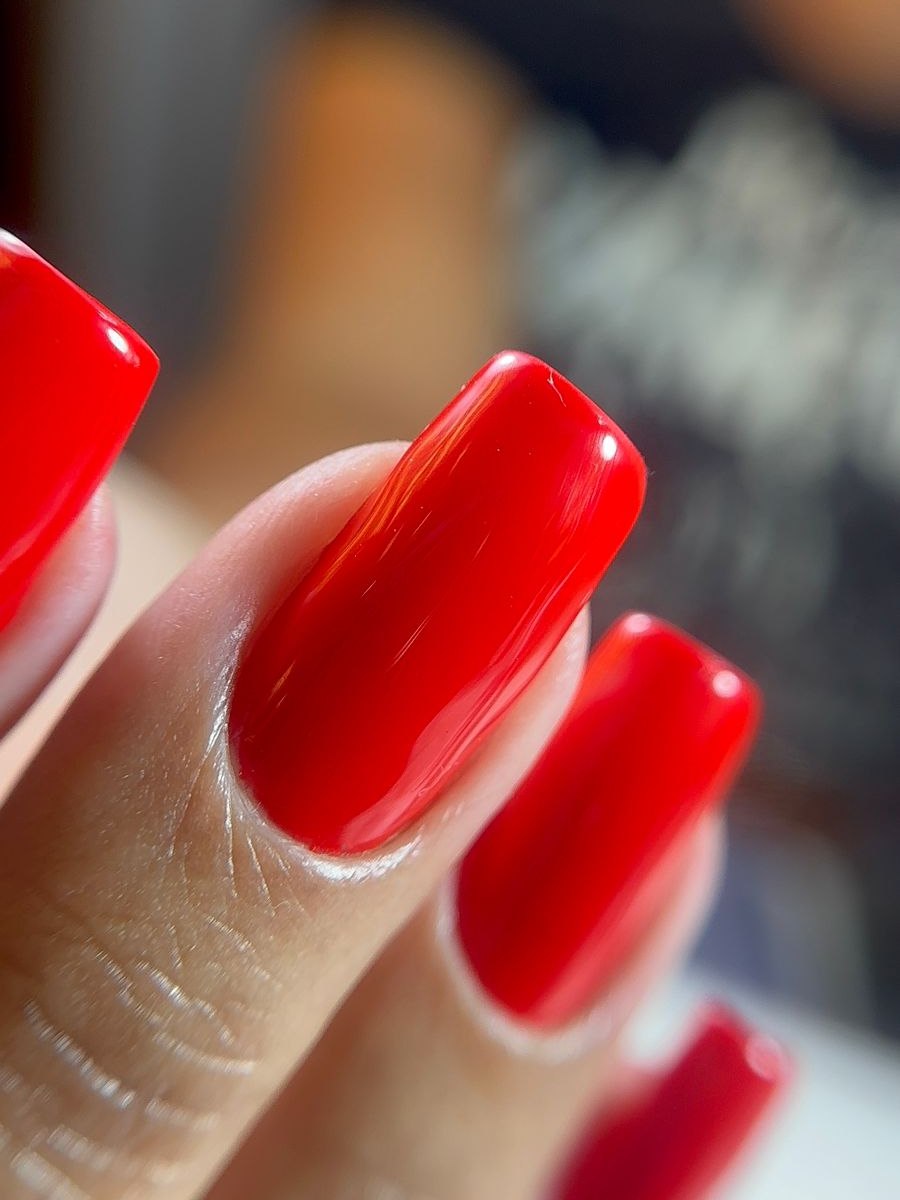 Esmaltação em gel vermelha com brilho espelhado, contorno limpo e encaixe preciso junto à cutícula